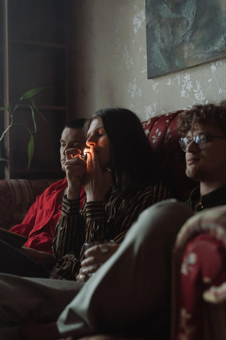three people on the couch smoking a joint