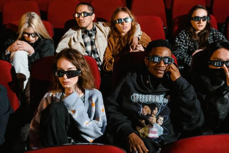 7 people watching a movie in a theater with 3D glasses on